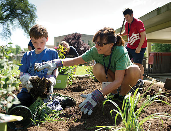 During the 2013 family camp, Theresa McKenna ’89 and her son, Carter, planted flowers at South Bend’s Healthwin Hospital.<br />
 photo: Matt Cashore ’94