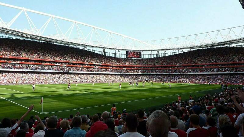 A photo of the pitch taken from the crowded stands at Emirates Stadium in London during a Premier League soccer game.