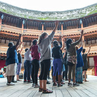 Robinson Shakespeare Company ensemble members raise their swords during a movement workshop on the stage at Shakespeare's Globe in London.