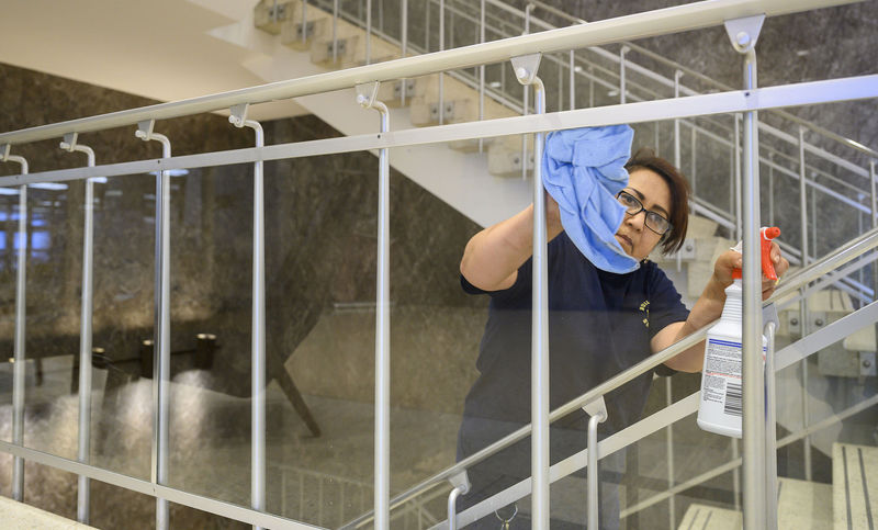Elia Romero disinfects a stairwell in the Hesburgh Library
