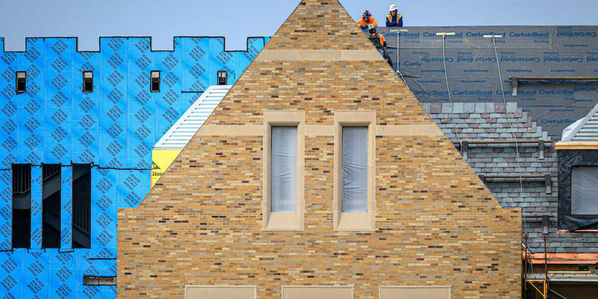 Construction workers stand on the roof of a science and engineering building project in progress.