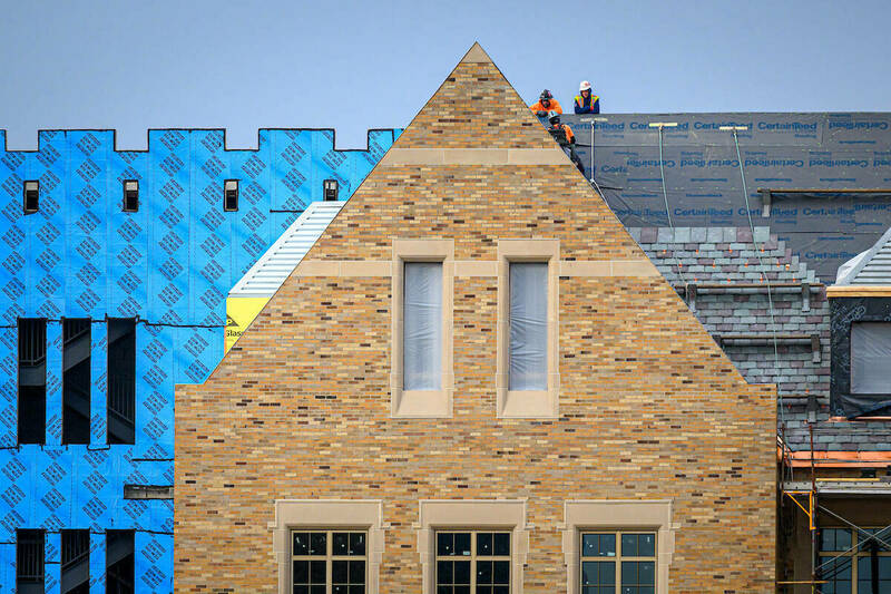 Construction workers stand on the roof of a science and engineering building project in progress.