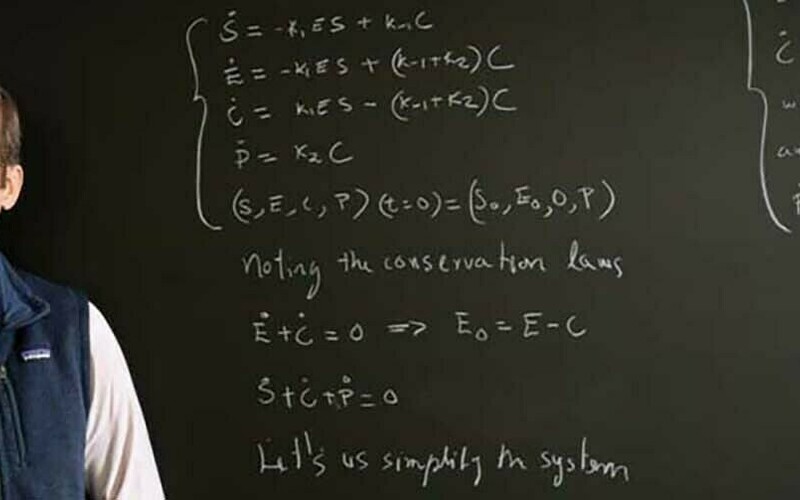 Science dean Santiago Schnell stands in front of a chalkboard covered in advanced equations.