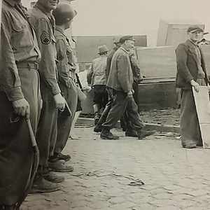 Bernard Cullen and fellow soldiers stand near displaced persons at a camp in Trier, Germany during World War II.