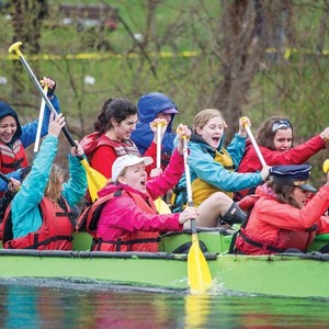 A group of students in different colored rain jackets compete in the Fisher Regatta on a soggy, gray day.