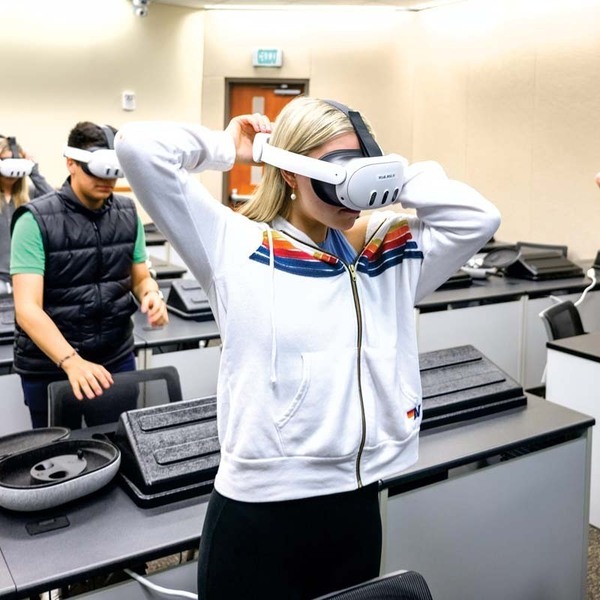 Rows of students put on virtual reality headsets in a classroom.