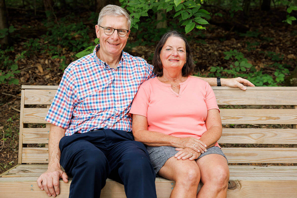 Deacon John Cord and his wife, Gwen, pose for a photo sitting on a bench.