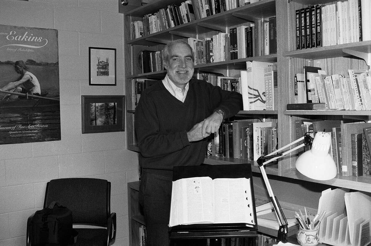 The late Ronald Weber poses for a photograph leaning against a bookshelf in his office
