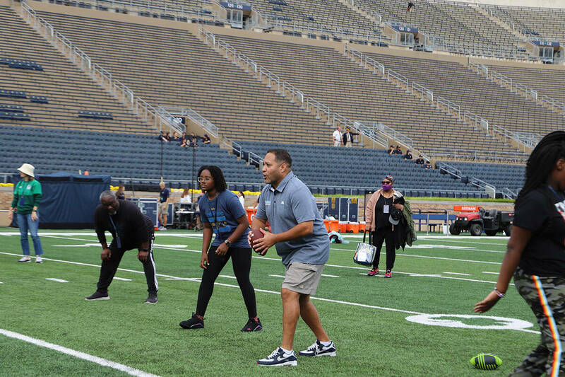 Greg Borkowski holds a football and calls signals for an impromptu play as others line up around him on the Notre Dame Stadium field during a Horizons for Youth visit