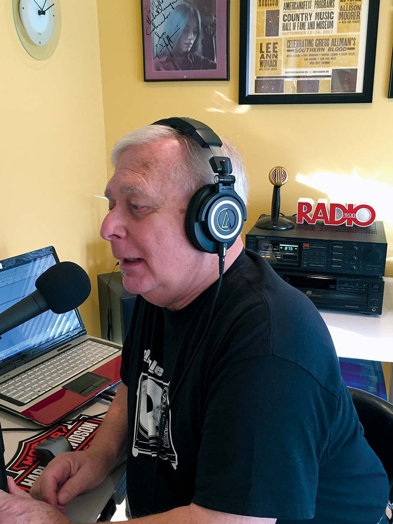 Mike Gianunzio wearing headphones and speaking into a microphone as he hosts his radio show Off-the-Beat