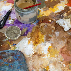 Many different shades of paint are smeared on an artist's palette.