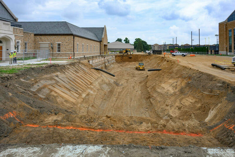 A big dirt hole showing the current construction site where the Shields Family Hall football facility will be built.