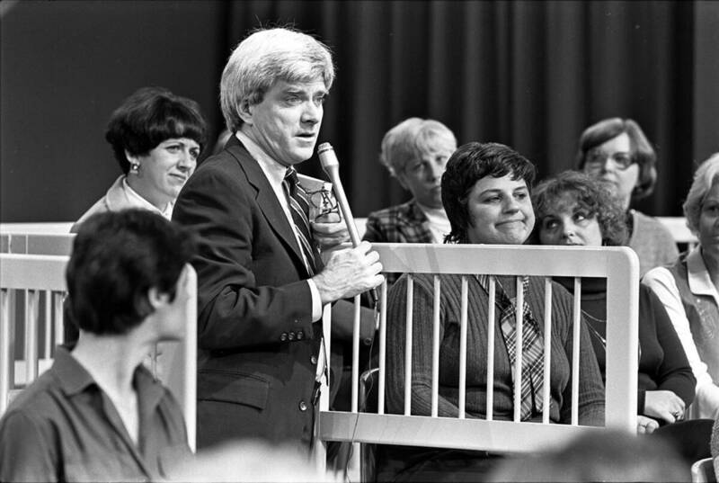 Talk show host Phil Donahue holds a microphone as he stands amid his audience during a 1980 broadcast.