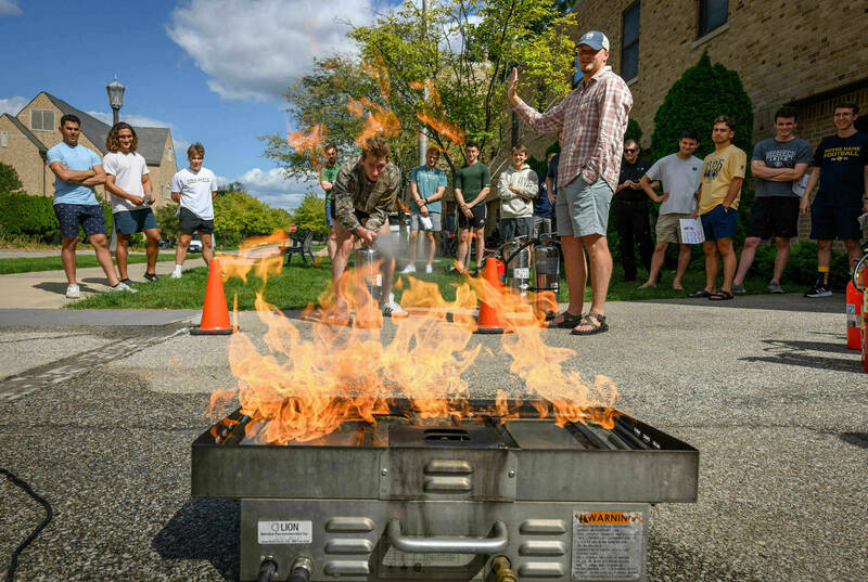 A controlled fire burns as a trainee resident assistant learns proper procedure for using an extinguisher