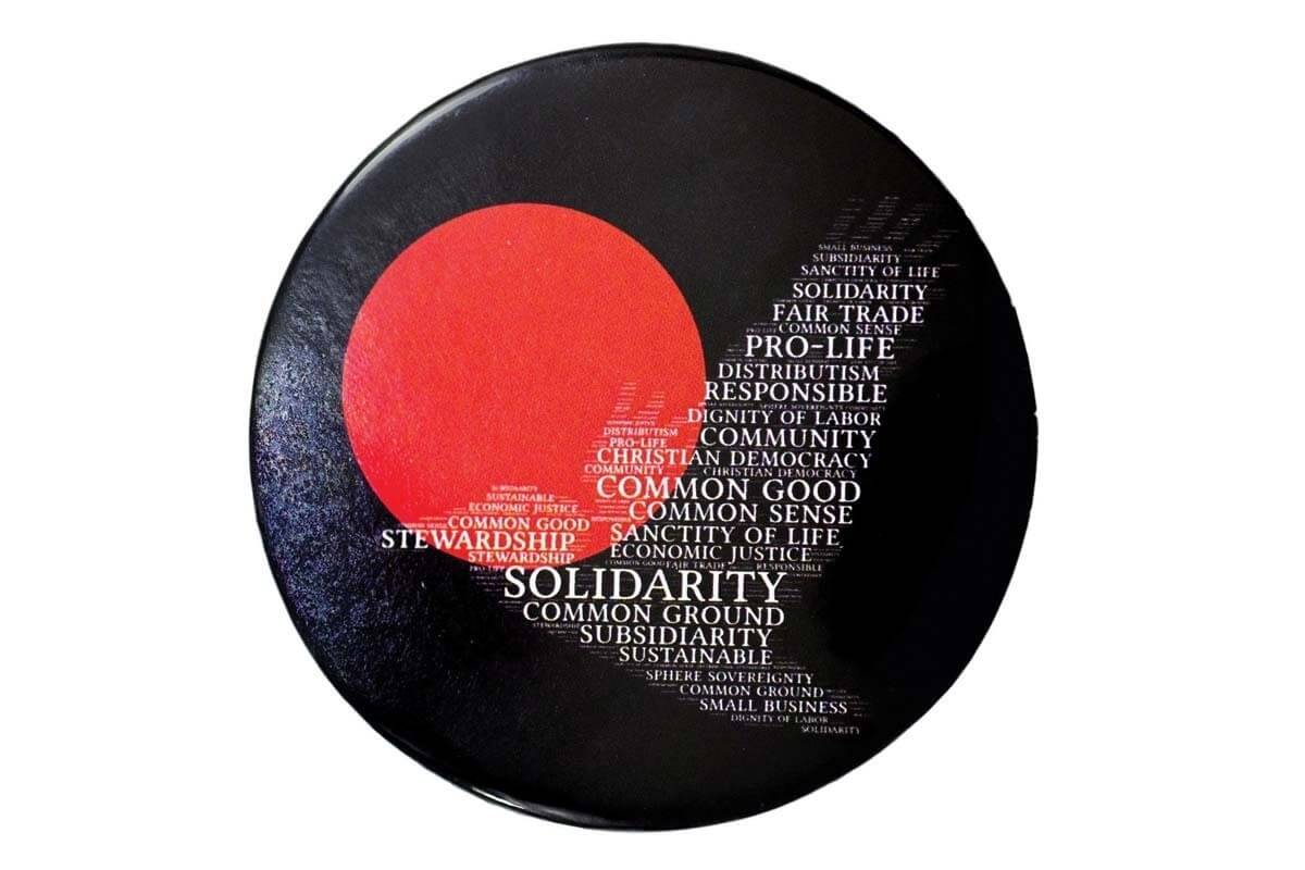 A black pin for the American Solidarity Party with a red circle and phrases such as "common good" "fair trade" and "pro life" that form a shape