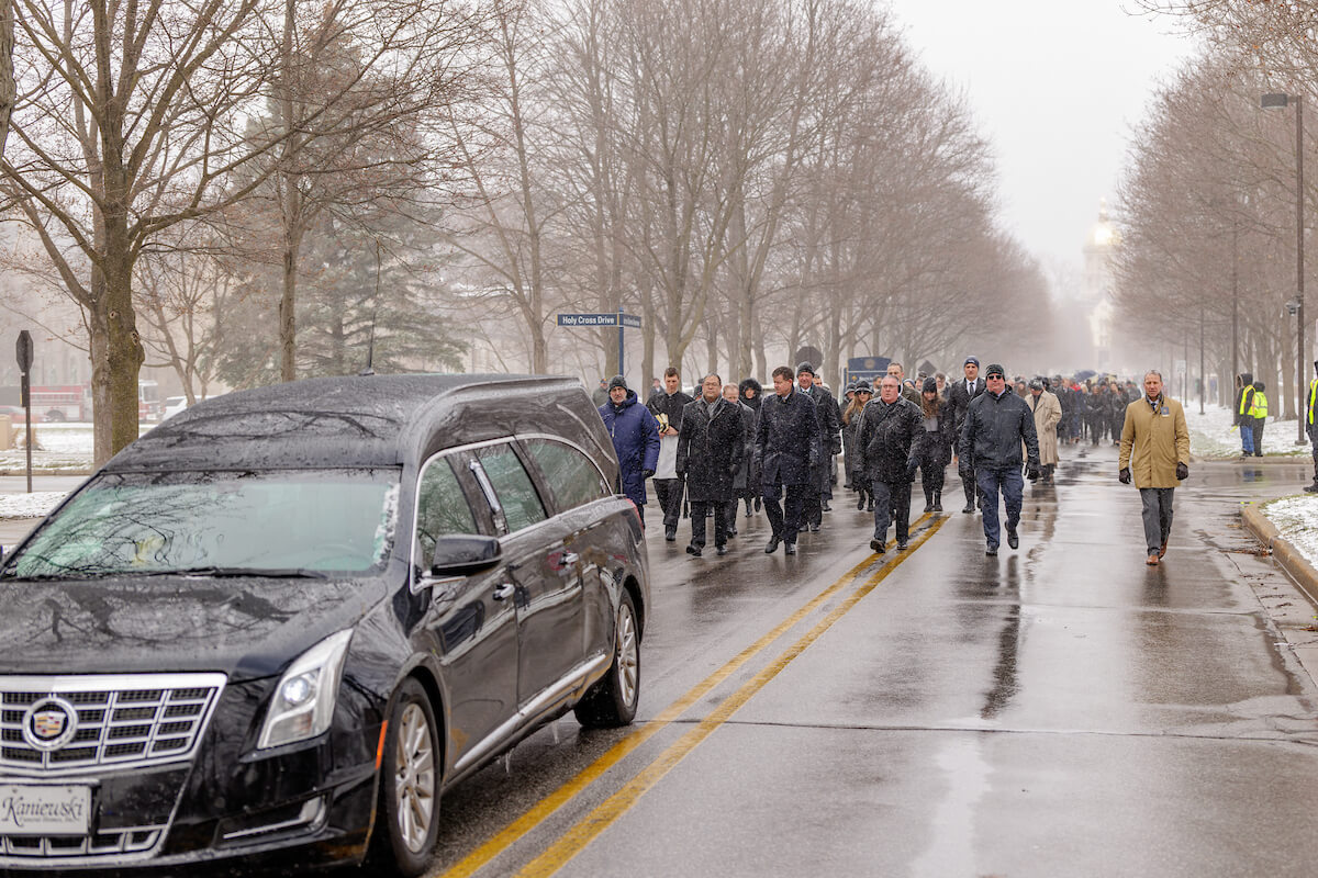 Friends and family follow a hearse in a procession along Notre Dame Avenue on a snowy day toward Cedar Grove Cemetery where Lou Holtz would be buried.