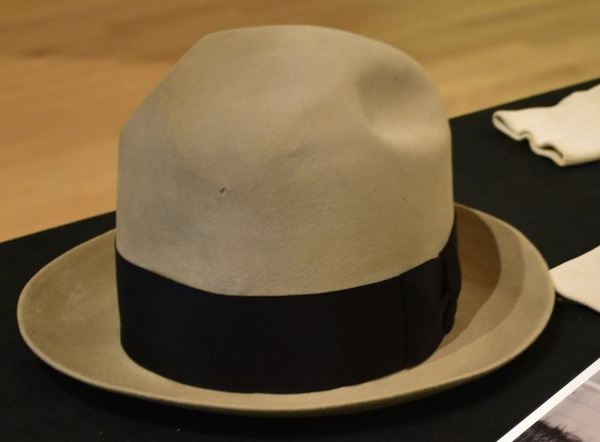 A light beige felt fedora-style hat with a black ribbon band.