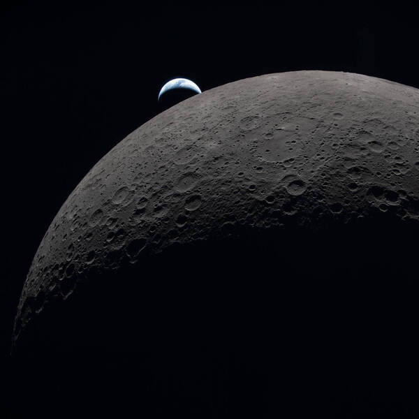 Heavily cratered gray Moon surface, with a blue and white crescent Earth rising above its dark horizon.