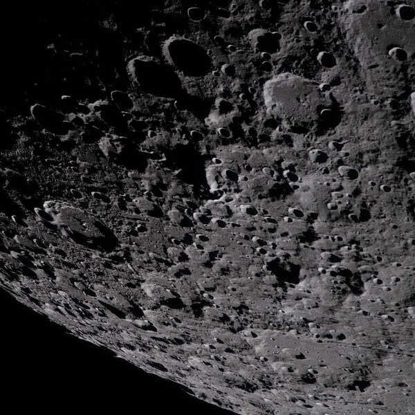 The heavily cratered gray surface of the Moon is illuminated, showing deep shadows from impacts against a black void.