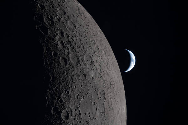 The heavily cratered gray surface of the Moon in the foreground with a crescent blue and white Earth in the dark background.