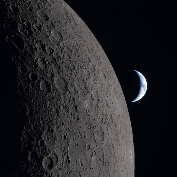 The heavily cratered gray surface of the Moon in the foreground with a crescent blue and white Earth in the dark background.