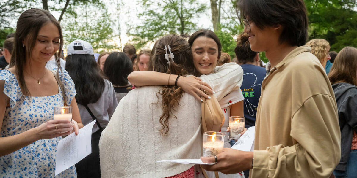 Students in the Class of 2024 hold candles and hug during their final visit to the Grotto.